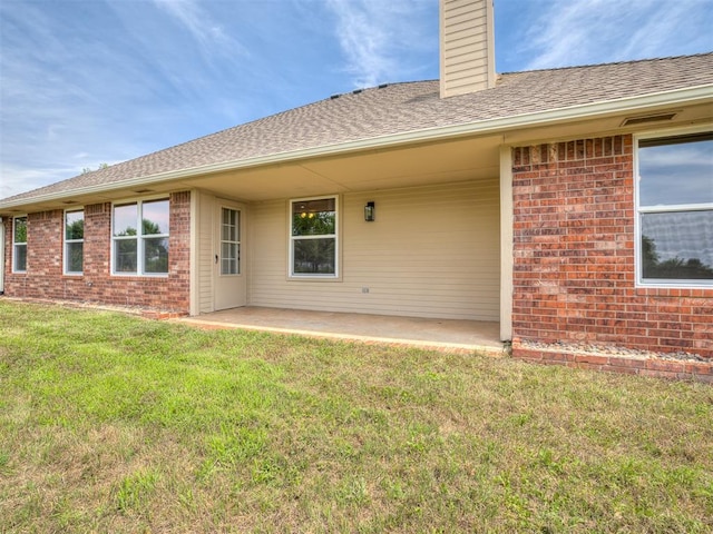 3922 Deer Xing, Edmond, OK 73025 - rear view of property with a chimney, a patio area, a lawn, brick siding, and roof with shingles