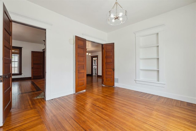 811 S Barker Ave, El Reno, OK 73036 - unfurnished room with built in shelves, a chandelier, and hardwood / wood-style floors