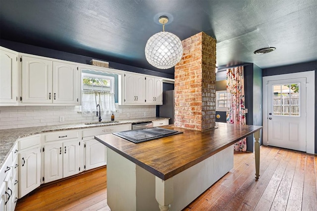811 S Barker Ave, El Reno, OK 73036 - kitchen with butcher block counters, white cabinets, light wood finished floors, decorative backsplash, and a textured ceiling