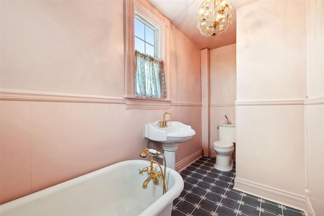 811 S Barker Ave, El Reno, OK 73036 - bathroom with a freestanding tub, tile patterned floors, a wainscoted wall, and a chandelier