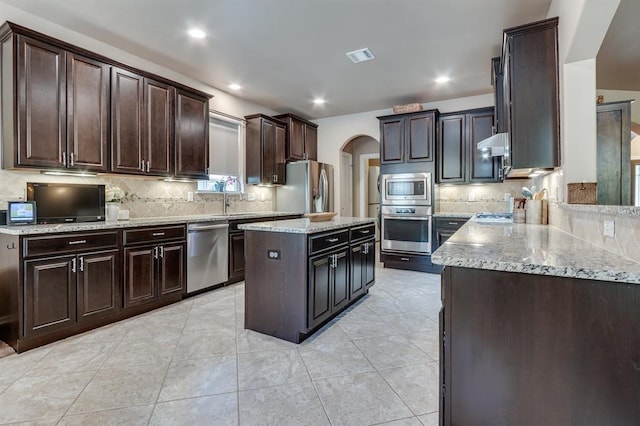 637 Branch Line Rd, Yukon, OK 73099 - kitchen featuring stainless steel appliances, arched walkways, decorative backsplash, light stone countertops, and recessed lighting