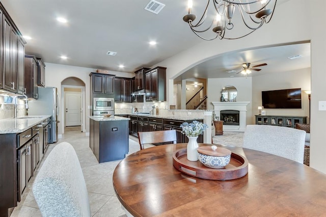 637 Branch Line Rd, Yukon, OK 73099 - dining area with arched walkways, a ceiling fan, a fireplace with raised hearth, light tile patterned flooring, and recessed lighting