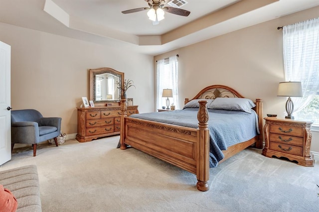 637 Branch Line Rd, Yukon, OK 73099 - bedroom with multiple windows, light colored carpet, a tray ceiling, and a ceiling fan