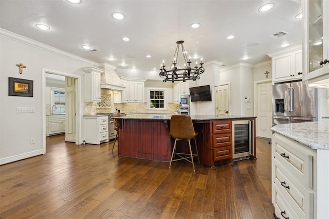 8700 N Waverly Ave, Oklahoma City, OK 73120 - kitchen with custom exhaust hood, beverage cooler, premium appliances, ornamental molding, and a chandelier