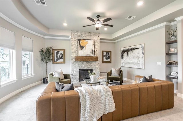 17817 Morning Sky Ct, Edmond, OK 73012 - living room with a tray ceiling, light colored carpet, a stone fireplace, recessed lighting, and ornamental molding