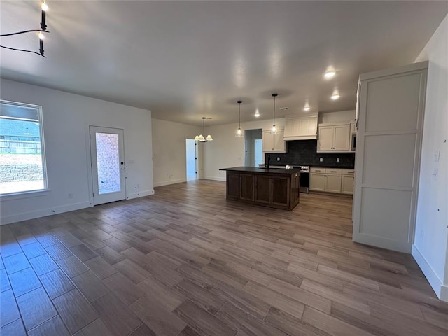 6101 Kinnick Dr, Edmond, OK 73034 - kitchen with open floor plan, a chandelier, dark countertops, backsplash, and premium range hood