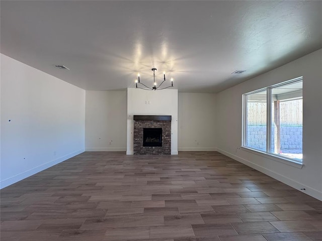 6101 Kinnick Dr, Edmond, OK 73034 - unfurnished living room featuring a chandelier, wood finished floors, and a fireplace