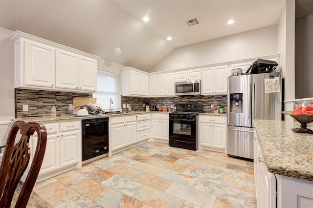 2732 SE 90th St, Moore, OK 73160 - kitchen featuring black appliances, tasteful backsplash, white cabinetry, vaulted ceiling, and stone tile flooring