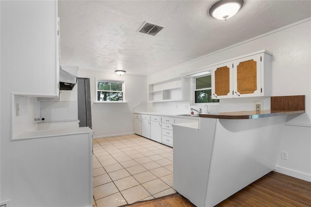 39525 W 151st St, Bristow, OK 74010 - kitchen with wall chimney range hood, a textured ceiling, white cabinetry, open shelves, and a peninsula