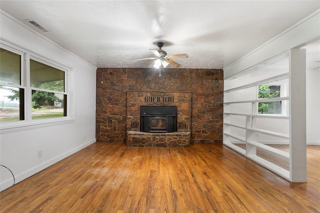 39525 W 151st St, Bristow, OK 74010 - unfurnished living room featuring a wood stove, wood finished floors, plenty of natural light, ceiling fan, and ornamental molding