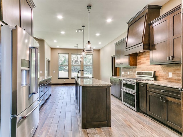 13524 SE 95th St, Oklahoma City, OK 73165 - kitchen with appliances with stainless steel finishes, dark brown cabinetry, tasteful backsplash, a center island with sink, and light stone counters