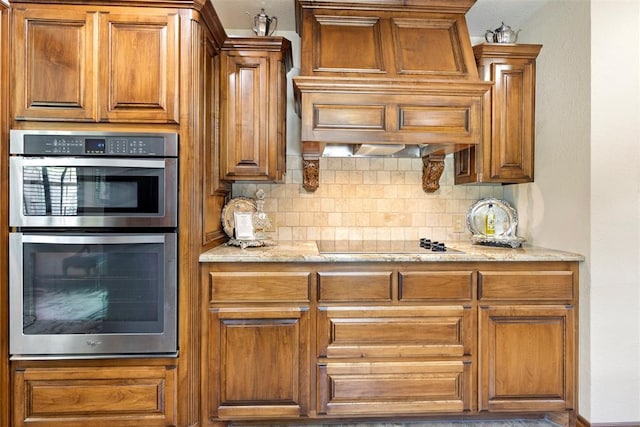 2 Terra Ln, Shawnee, OK 74804 - kitchen with stainless steel double oven, black electric stovetop, decorative backsplash, brown cabinets, and light stone counters