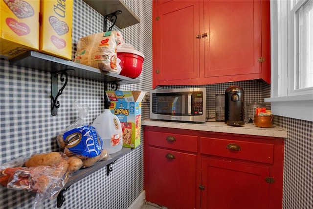 201 S Park Rd, Hobart, OK 73651 - kitchen featuring stainless steel microwave, red cabinetry, light countertops, open shelves, and backsplash