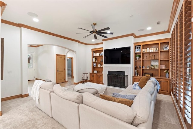1900 Cobblestone Dr, Shawnee, OK 74804 - living area with arched walkways, light colored carpet, a ceiling fan, a fireplace, and crown molding