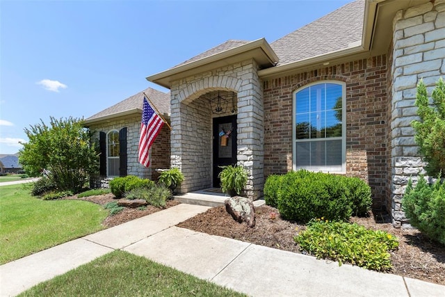1900 Cobblestone Dr, Shawnee, OK 74804 - view of exterior entry with brick siding, a shingled roof, and a yard