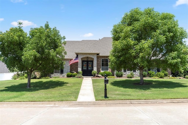 1900 Cobblestone Dr, Shawnee, OK 74804 - french country inspired facade featuring french doors, a front lawn, stone siding, and a shingled roof
