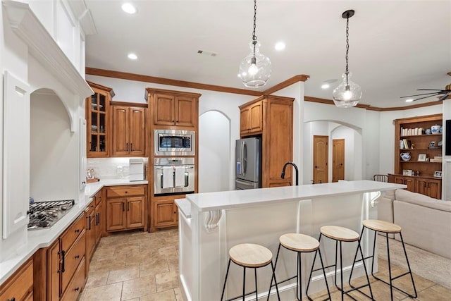 1900 Cobblestone Dr, Shawnee, OK 74804 - kitchen with arched walkways, appliances with stainless steel finishes, a kitchen bar, brown cabinets, and open floor plan