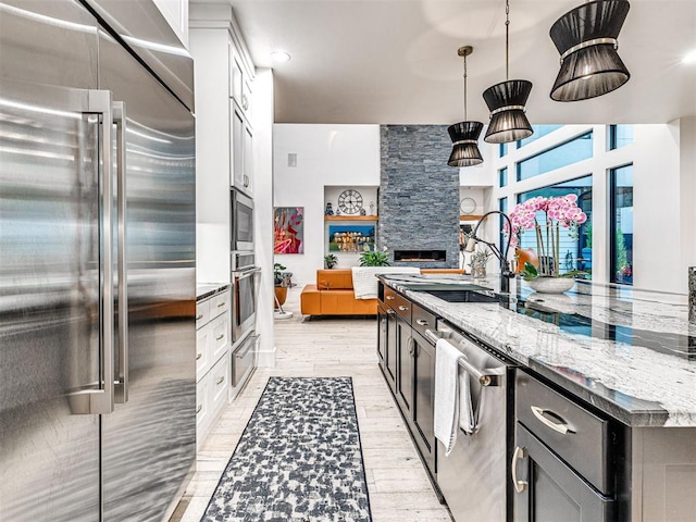 2824 Guilford Ln, Oklahoma City, OK 73120 - kitchen featuring appliances with stainless steel finishes, open floor plan, light stone counters, light wood-type flooring, and pendant lighting