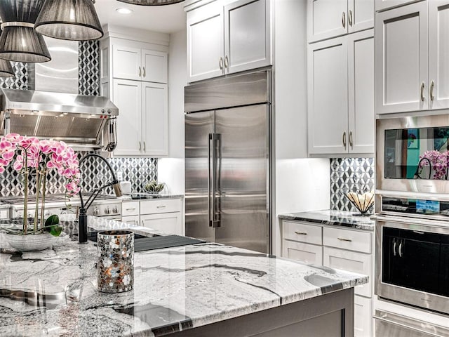 2824 Guilford Ln, Oklahoma City, OK 73120 - kitchen featuring stainless steel appliances, decorative backsplash, wall chimney exhaust hood, a warming drawer, and light stone counters