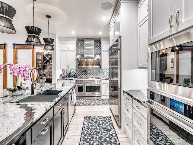 2824 Guilford Ln, Oklahoma City, OK 73120 - kitchen featuring wall chimney range hood, premium appliances, decorative backsplash, light stone countertops, and white cabinetry