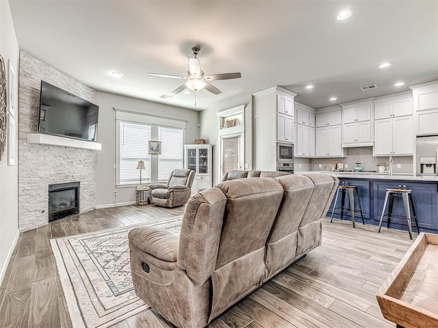 11104 Fairways Ave, Yukon, OK 73099 - living room with a ceiling fan, light wood-type flooring, recessed lighting, and a stone fireplace