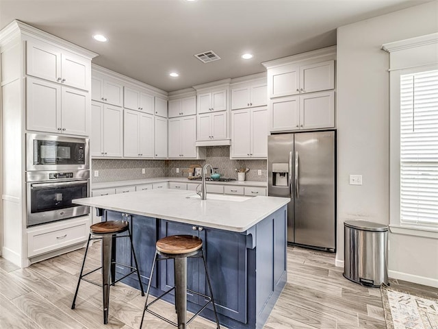 11104 Fairways Ave, Yukon, OK 73099 - kitchen featuring stainless steel appliances, light wood finished floors, a breakfast bar area, white cabinets, and recessed lighting