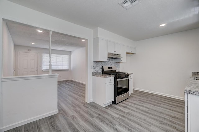 1409 Mcdonald Dr, Midwest City, OK 73130 - kitchen with stainless steel range with gas cooktop, under cabinet range hood, light wood-style flooring, tasteful backsplash, and white cabinets