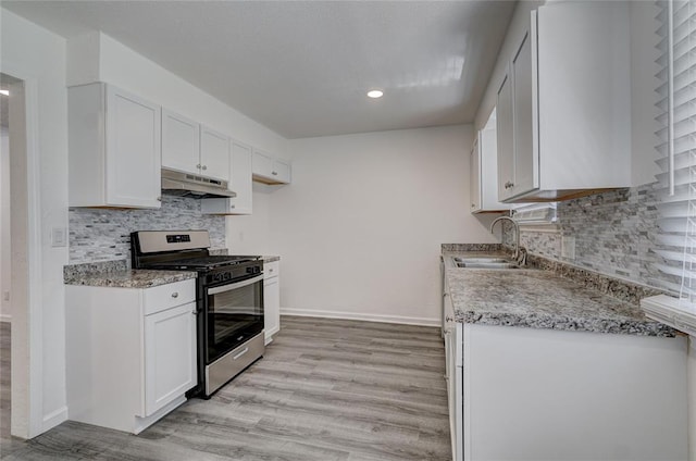 1409 Mcdonald Dr, Midwest City, OK 73130 - kitchen with stainless steel gas range, under cabinet range hood, light wood finished floors, tasteful backsplash, and recessed lighting