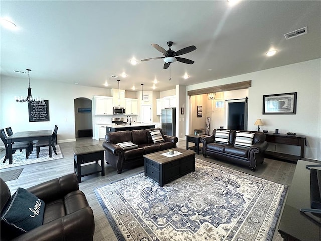 5557 Coker Rd, Shawnee, OK 74804 - living area with a ceiling fan, arched walkways, wood finished floors, and a chandelier