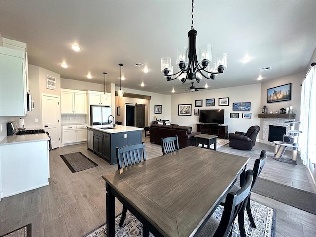 5557 Coker Rd, Shawnee, OK 74804 - dining area featuring a fireplace, a chandelier, light wood finished floors, a ceiling fan, and recessed lighting