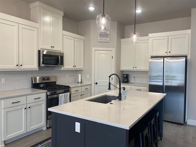 5557 Coker Rd, Shawnee, OK 74804 - kitchen featuring appliances with stainless steel finishes, backsplash, wood finished floors, a center island with sink, and light stone countertops