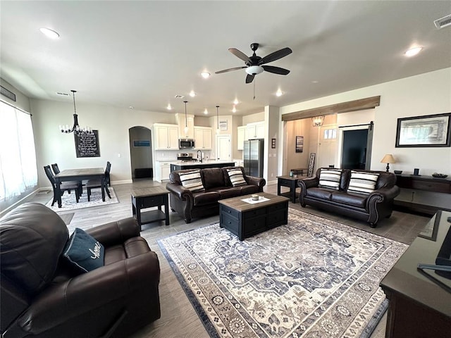 5557 Coker Rd, Shawnee, OK 74804 - living room featuring a ceiling fan, recessed lighting, arched walkways, a chandelier, and light wood-type flooring
