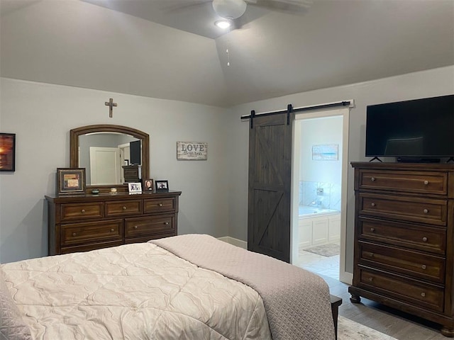 5557 Coker Rd, Shawnee, OK 74804 - bedroom with a barn door, lofted ceiling, ensuite bathroom, wood finished floors, and ceiling fan