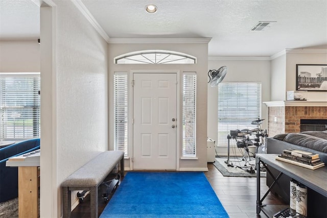 1800 NW 161st Pl, Edmond, OK 73013 - entryway with wood finished floors, ornamental molding, a textured ceiling, and a brick fireplace