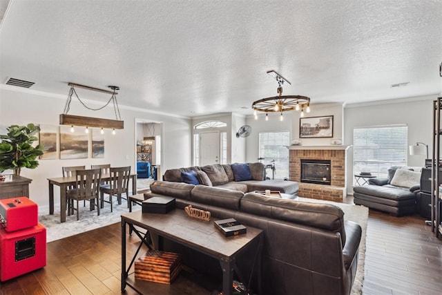 1800 NW 161st Pl, Edmond, OK 73013 - living area featuring dark wood-style flooring, plenty of natural light, a textured ceiling, ornamental molding, and a fireplace