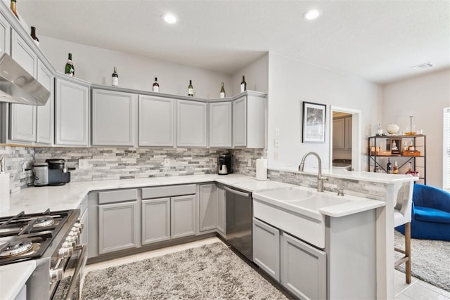 1800 NW 161st Pl, Edmond, OK 73013 - kitchen featuring gray cabinets, stainless steel appliances, a peninsula, decorative backsplash, and a breakfast bar area