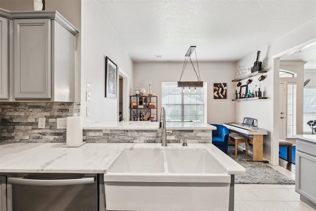 1800 NW 161st Pl, Edmond, OK 73013 - kitchen with stainless steel dishwasher, gray cabinetry, backsplash, light tile patterned floors, and light stone counters