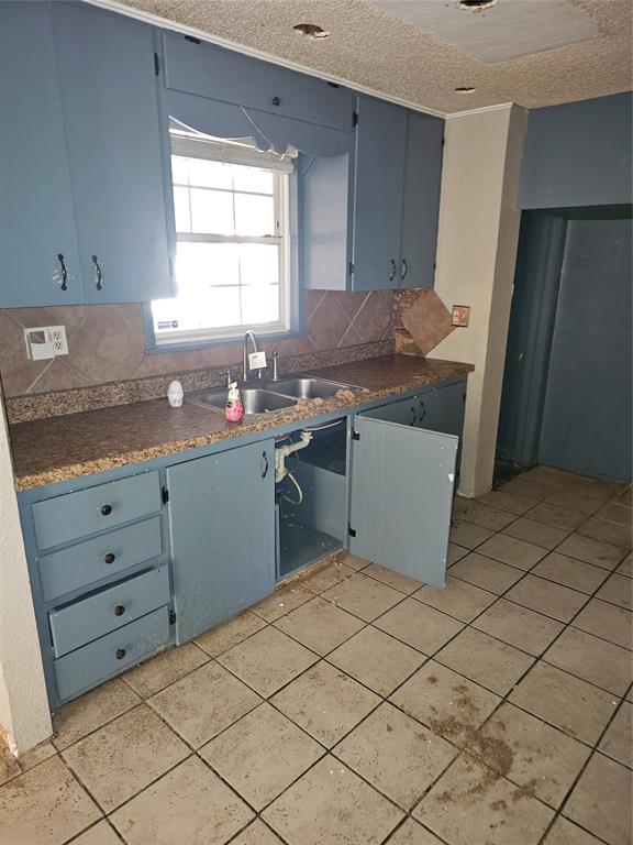 1137 Mallard Dr, Del City, OK 73115 - kitchen with blue cabinetry, tasteful backsplash, dark countertops, and a textured ceiling