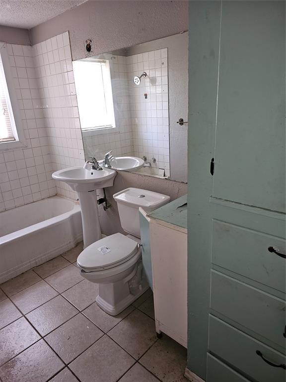 1137 Mallard Dr, Del City, OK 73115 - bathroom featuring a textured ceiling, tile patterned flooring, and washtub / shower combination