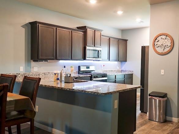 1016 NW 4th St, Newcastle, OK 73065 - kitchen with stainless steel appliances, a peninsula, stone countertops, and dark brown cabinetry