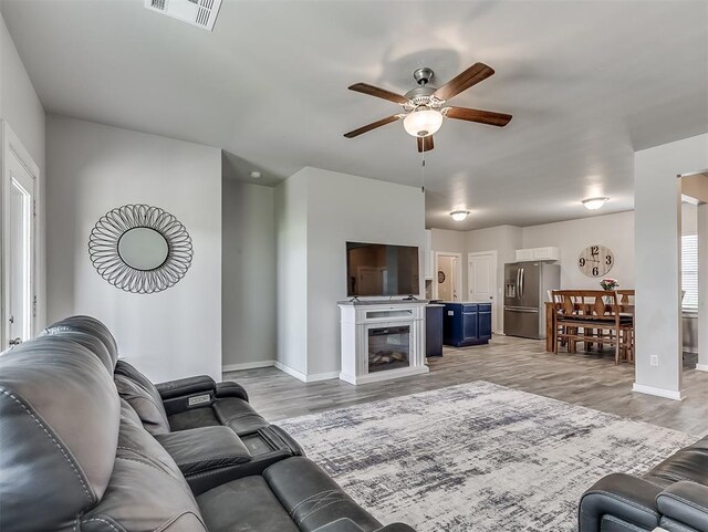 14325 Meadow Ridge Ln, Edmond, OK 73025 - living room with ceiling fan, light wood finished floors, and a glass covered fireplace