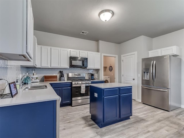 14325 Meadow Ridge Ln, Edmond, OK 73025 - kitchen with stainless steel appliances, blue cabinetry, a center island, light countertops, and decorative backsplash