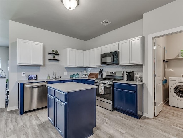 14325 Meadow Ridge Ln, Edmond, OK 73025 - kitchen featuring appliances with stainless steel finishes, blue cabinets, washer / clothes dryer, light countertops, and decorative backsplash