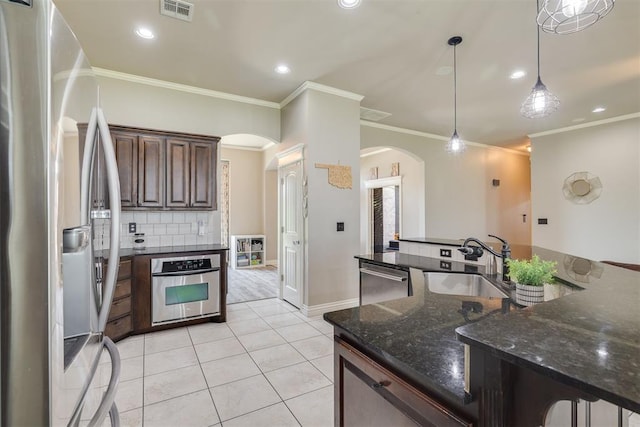 4501 NW 164th Ter, Edmond, OK 73013 - kitchen with stainless steel appliances, arched walkways, ornamental molding, decorative backsplash, and light tile patterned floors