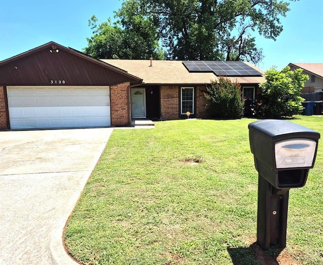 3120 Del Rey Dr, Midwest City, OK 73110 - ranch-style home featuring brick siding, roof mounted solar panels, a front lawn, and concrete driveway