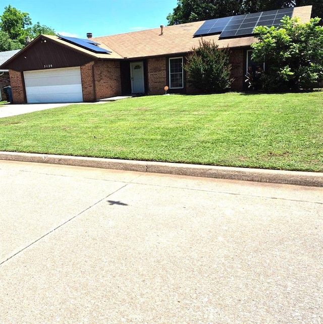 3120 Del Rey Dr, Midwest City, OK 73110 - ranch-style home featuring solar panels, a front yard, a garage, concrete driveway, and brick siding