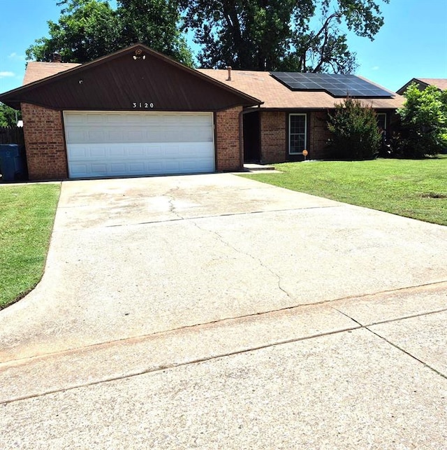 3120 Del Rey Dr, Midwest City, OK 73110 - single story home featuring brick siding, solar panels, a front lawn, driveway, and an attached garage