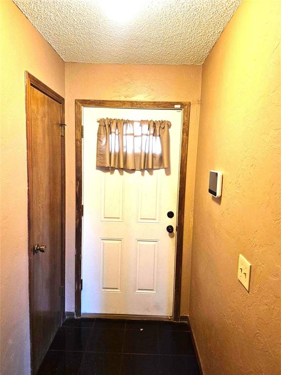 3120 Del Rey Dr, Midwest City, OK 73110 - entryway featuring a textured ceiling and dark tile patterned floors
