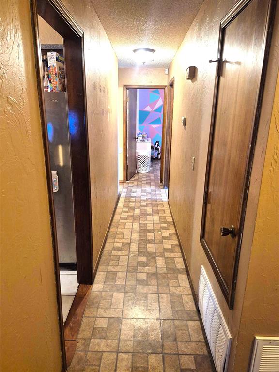 3120 Del Rey Dr, Midwest City, OK 73110 - hall with brick patterned flooring, a textured ceiling, and a textured wall