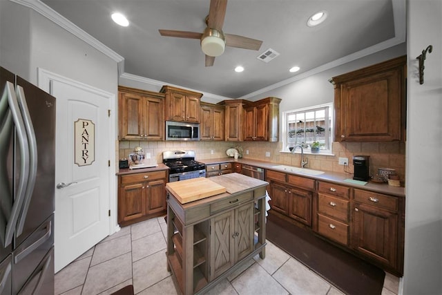 1840 Kamber Ter, Edmond, OK 73003 - kitchen featuring appliances with stainless steel finishes, wooden counters, a ceiling fan, decorative backsplash, and ornamental molding
